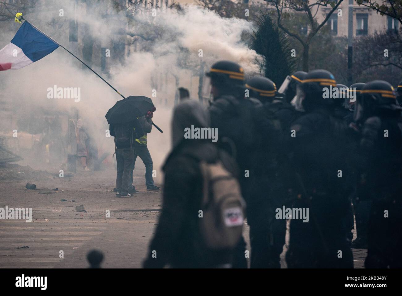 Un protester del blocco nero con un ombrello passa vicino alla polizia tumulto, questo Sabato, 16 novembre 2019, mentre si è svolto a Parigi l'evento anniversario dei giubbotti gialli per il 1 anno del movimento. Una grande manifestazione è stata quella di svolgersi tra Place d'Italie e la Gare du Nord, ma dopo scene di violenza tra il blocco nero e la polizia, la prefettura ha annullato la marcia che ha lasciato il posto a scene di caos . (Foto di Samuel Boivin/NurPhoto) Foto Stock