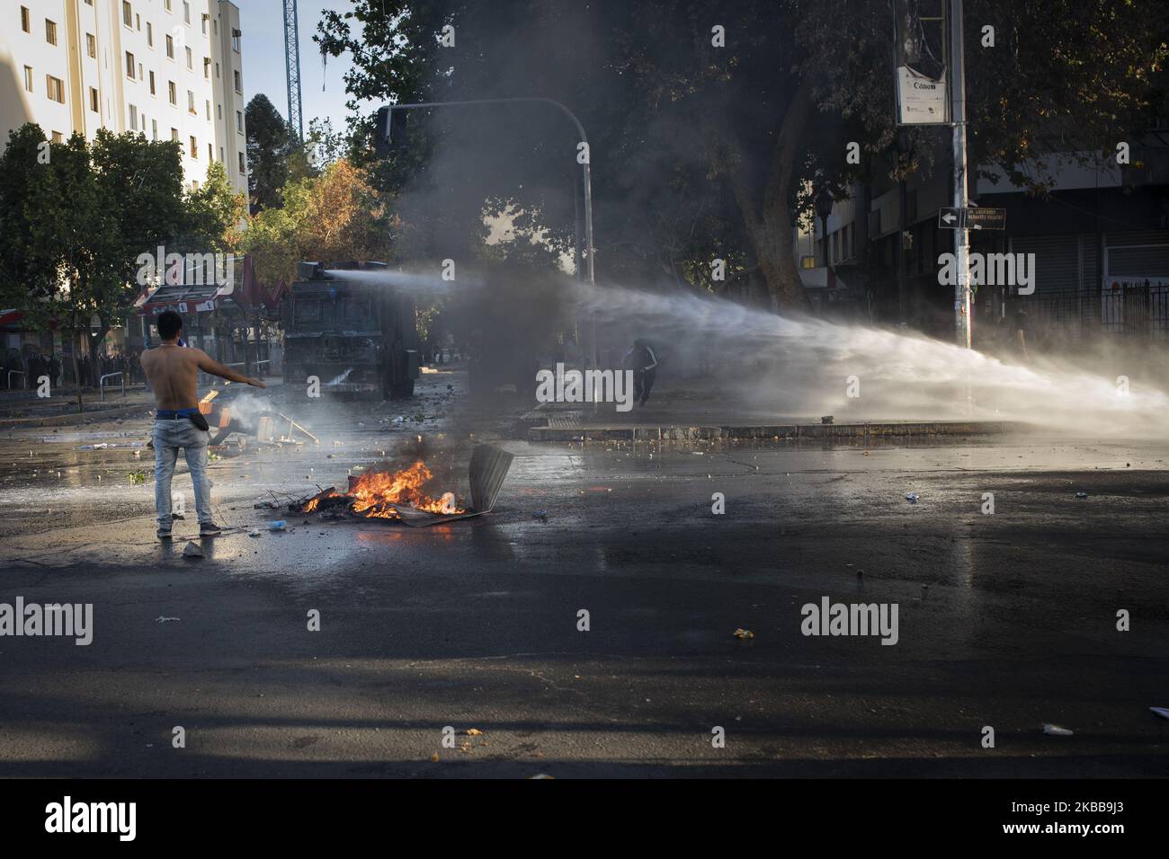 I dimostranti corrono come un veicolo di polizia utilizza il suo cannone ad acqua durante una protesta anti-governativa a Santiago, Cile, 31 ottobre 2019. (Foto di Jeremias Gonzalez/NurPhoto) Foto Stock