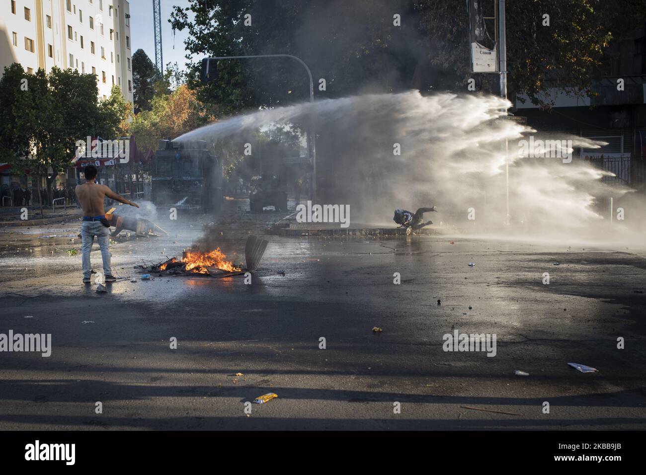 I dimostranti corrono come un veicolo di polizia utilizza il suo cannone ad acqua durante una protesta anti-governativa a Santiago, Cile, 31 ottobre 2019. (Foto di Jeremias Gonzalez/NurPhoto) Foto Stock