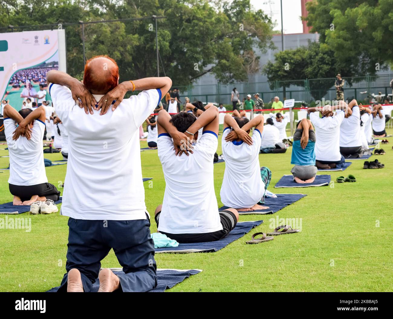 Sessione di esercizi di Group Yoga per persone di diverse età allo stadio di cricket a Delhi in occasione della Giornata Internazionale di Yoga, un grande gruppo di adulti che frequentano Yo Foto Stock
