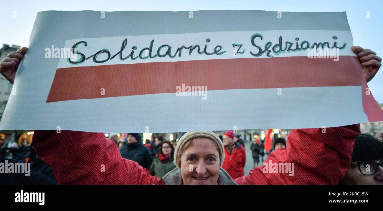 Una signora ha il vessillo di 'solidarietà con i giudici' durante un'altra solidarietà con la protesta dei giudici molestati nella piazza principale del Martket di Cracovia. Alcune centinaia di persone, principalmente membri del Comitato per la Difesa della democrazia di Cracovia (polacco: KOD) e dei loro sostenitori, si sono unite questa sera ad altri manifestanti che si accaniscono nel paese per esprimere la loro solidarietà ai giudici durante il "noi lo facciamo per tutti - solidarietà ai giudici!” protesta. Domenica 1 dicembre 2019 a Cracovia, Polonia. (Foto di Artur Widak/NurPhoto) Foto Stock