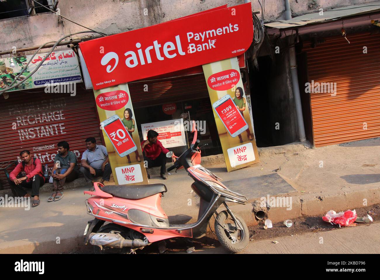 People rest in front of a shop with an advertisement of India’s telecom giant Bharti Airtel in Mumbai, India on 18 December 2019. (Photo by Himanshu Bhatt/NurPhoto) Foto Stock