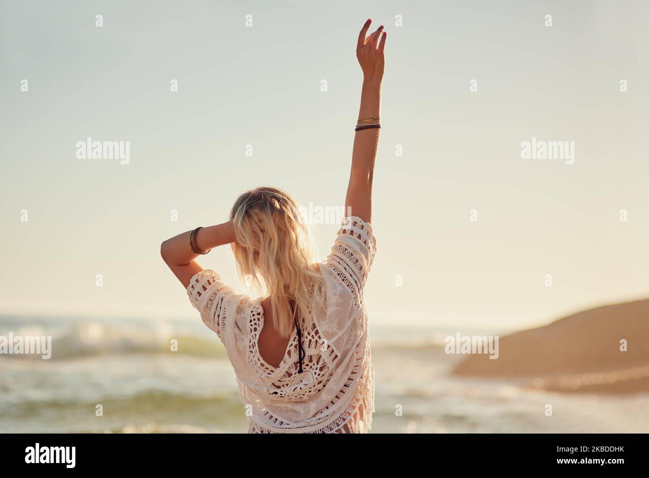 La spiaggia è dove mi sento più libero. Ripresa di una giovane donna sulla spiaggia con la mano in aria. Foto Stock