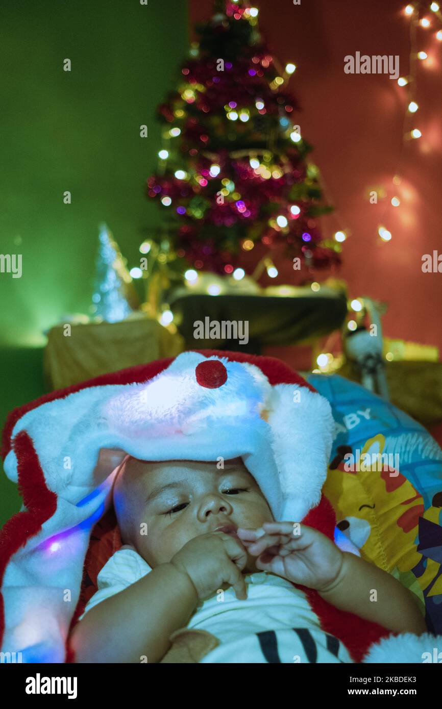 Un bambino con albero di Natale e spruzzi di luci sullo sfondo il 24 dicembre 2018 a Pekanbaru, Indonesia (Photo by Afrianto Silalahi/NurPhoto) Foto Stock