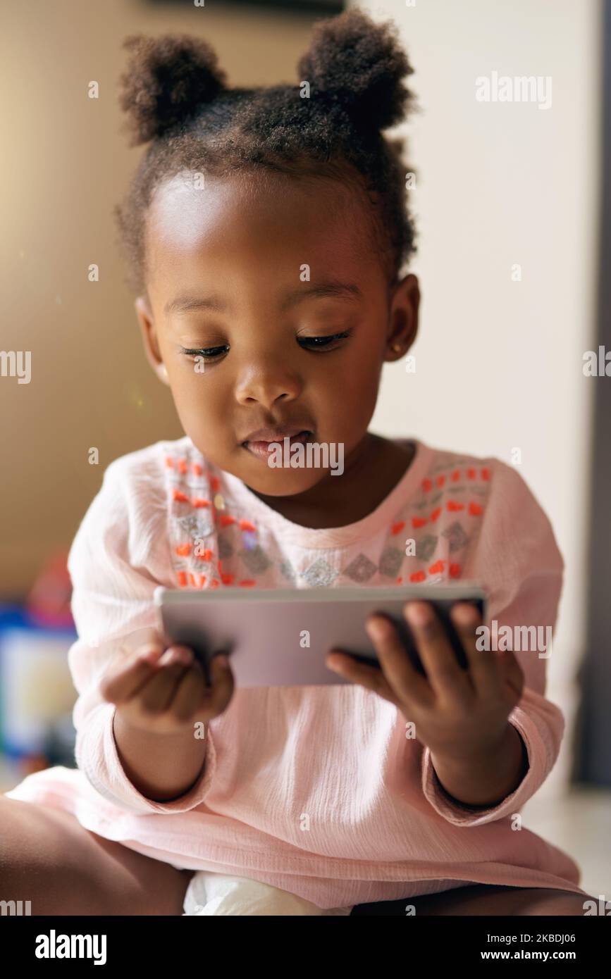 Crescere in un'era tecnologica. Una bambina adorabile che usa il suo tablet a casa. Foto Stock