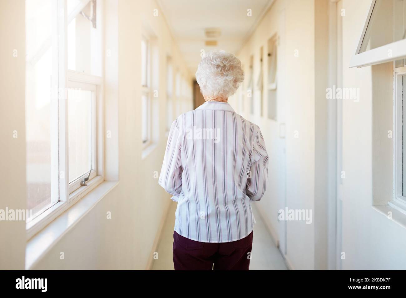 Dove chiama a casa ora. Ripresa da dietro di una donna anziana che cammina lungo un corridoio in una casa di riposo. Foto Stock