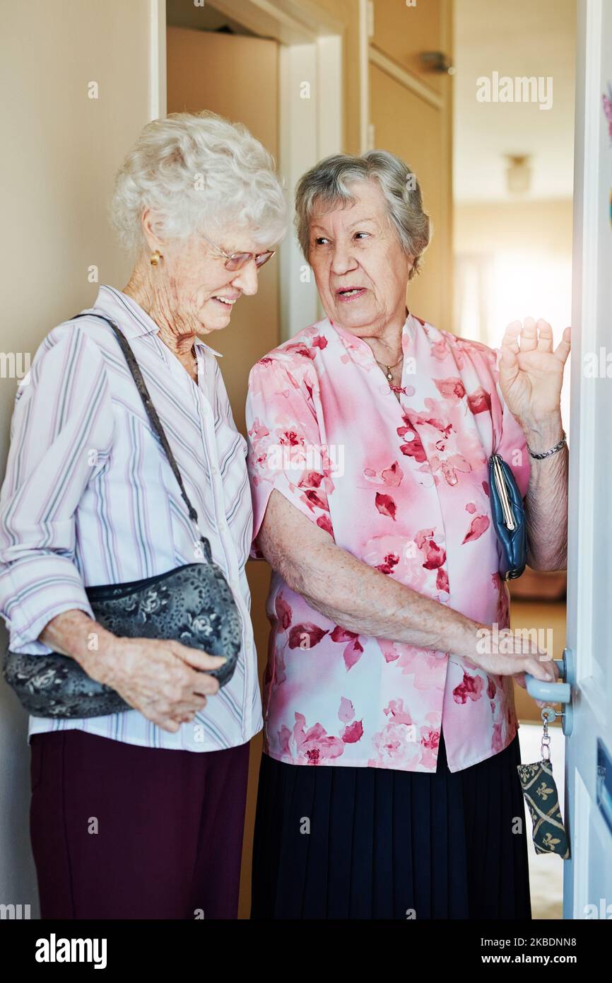 Dobbiamo porre un altro lucchetto di sicurezza in questa sede: Due donne anziane che chiudono la porta prima di uscire. Foto Stock