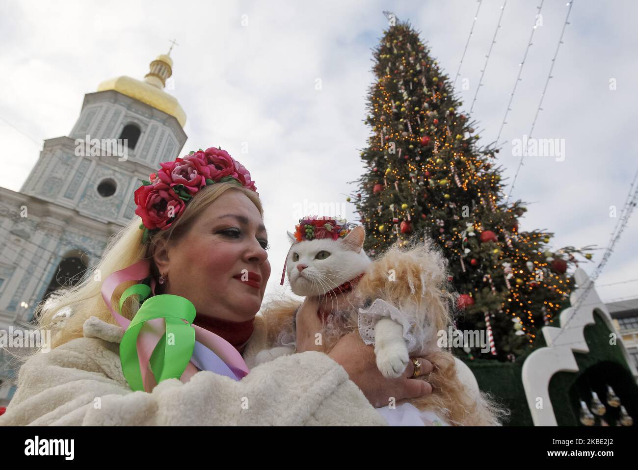Una donna tiene il suo gatto vestito in costume folcloristico, durante una  celebrazione nella piazza di Santa Sofia a Kyiv, Ucraina, il 7 gennaio  2020. Gli ucraini segnano il tradizionale giorno di