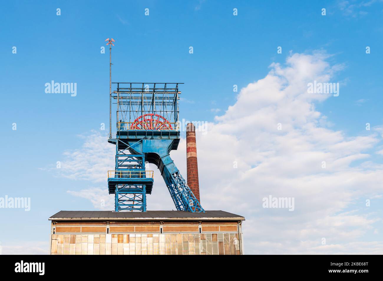 Vecchio albero di miniera di carbone arrugginito. Sullo sfondo il camino dell'impianto di riscaldamento Foto Stock