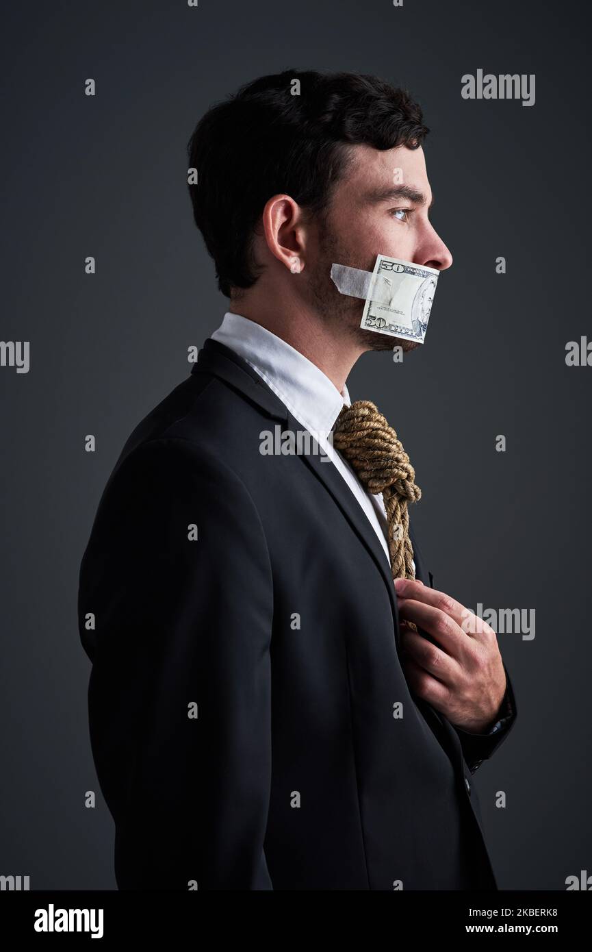 Le bugie non hanno futuro nel commercio. Studio shot di un uomo d'affari con corda intorno al collo e denaro tappato sopra la bocca su uno sfondo grigio. Foto Stock