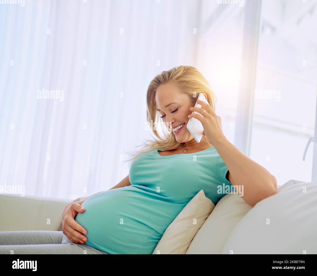 Sì, sono sicuro di crescere e di essere incandescente. Una donna incinta che parla su un cellulare a casa. Foto Stock