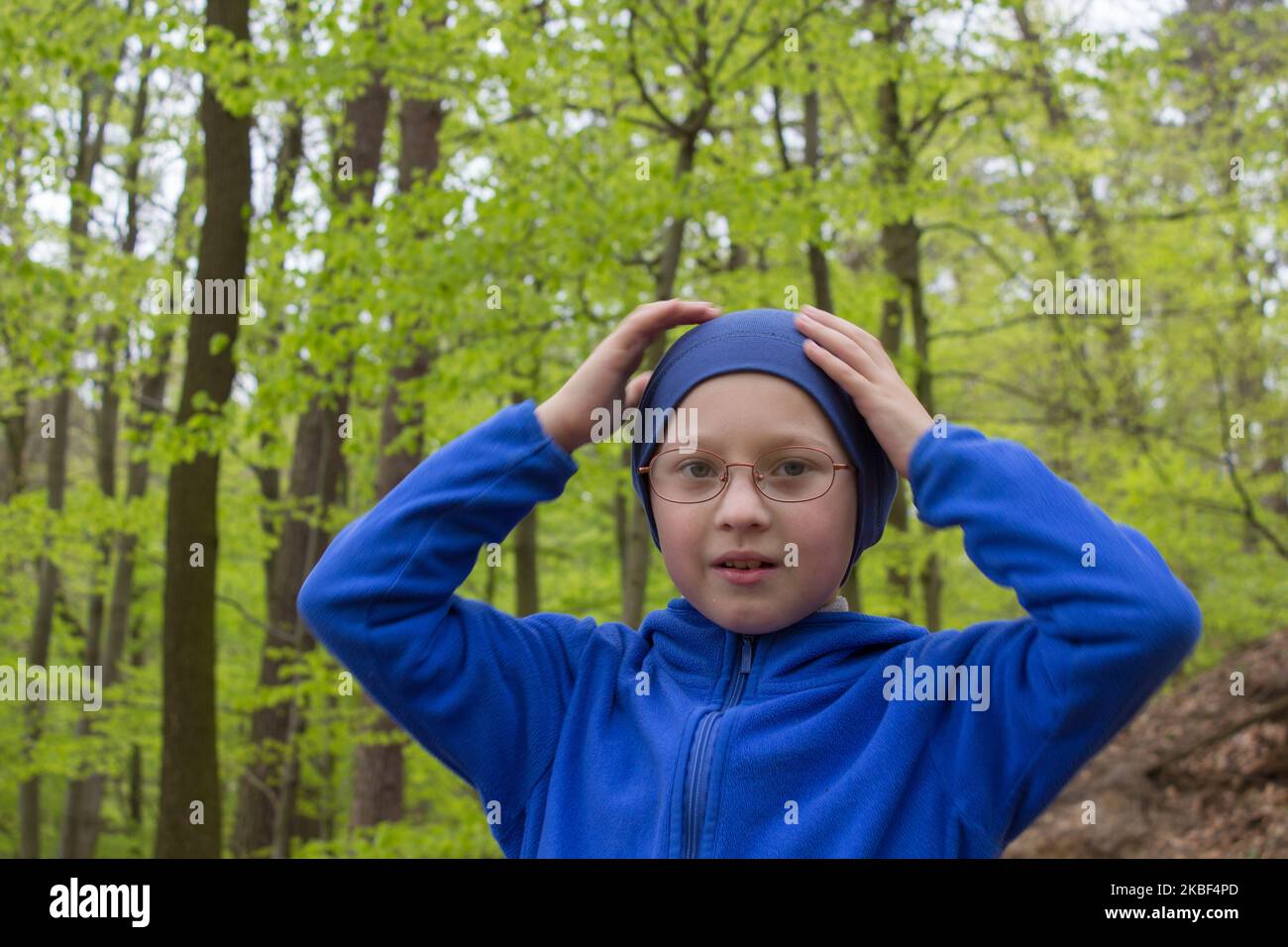 l'emozione del ragazzo si è dimenticata nella foresta dove andare, il ragazzo tiene le mani dietro la testa, perdita di memoria Foto Stock