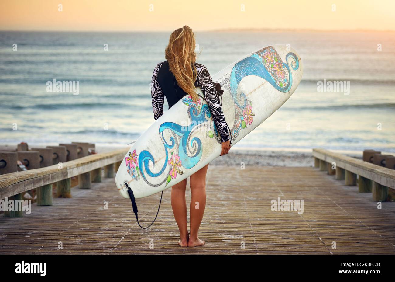 L'oceano sta chiamando. Ripresa retroversa di una giovane surfista irriconoscibile in piedi con la tavola da surf che guarda sopra l'oceano. Foto Stock