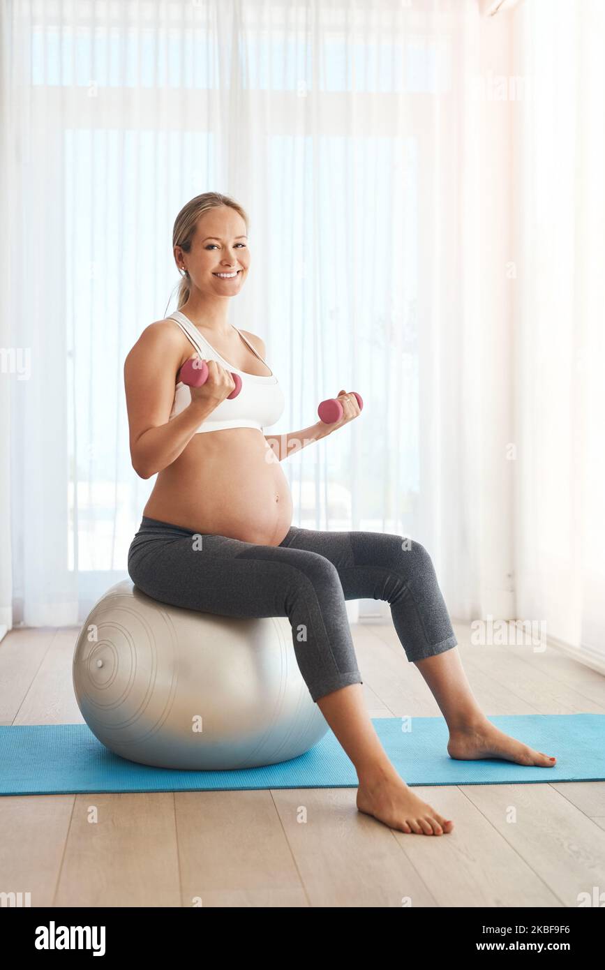 L'esercitazione fa i wonders per la mamma ed il bambino. Una donna incinta che lavora fuori con una sfera di esercitazione ed i pesi nel paese. Foto Stock
