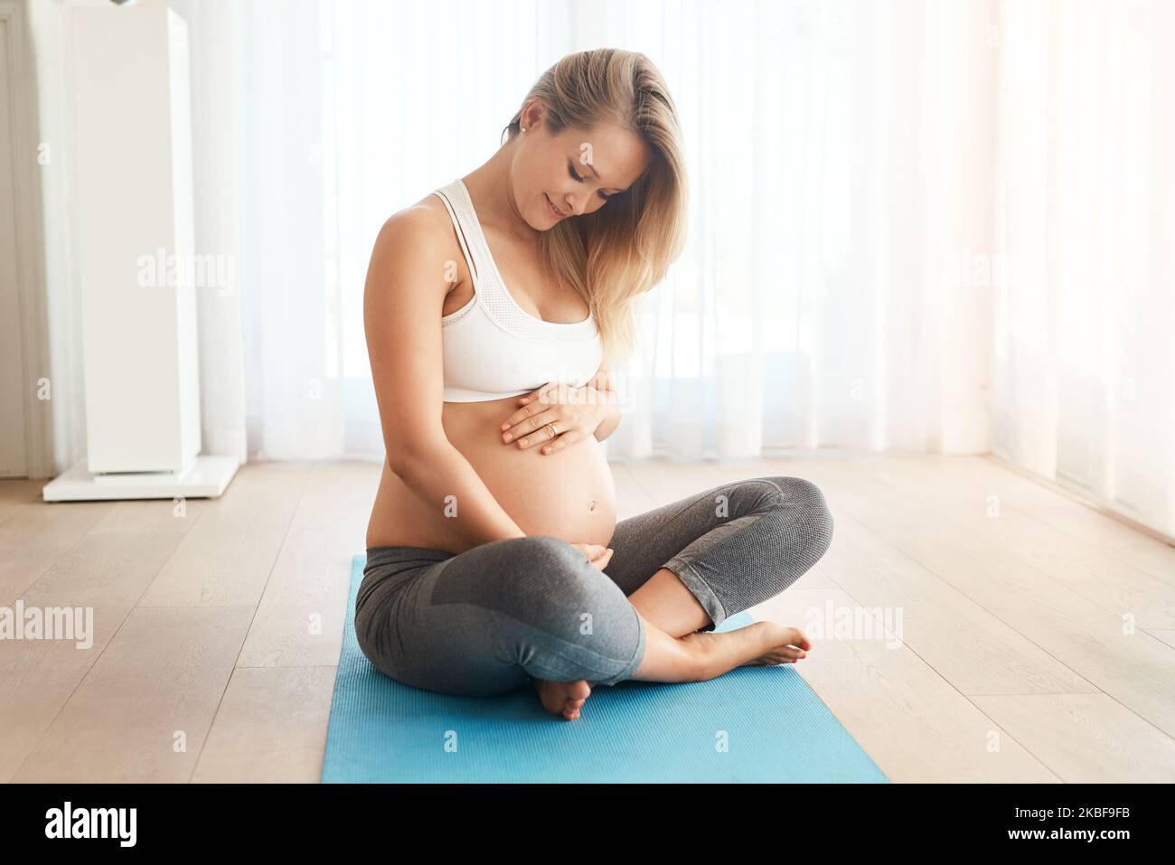 Dare al bambino il dono di una mamma sana. Una donna incinta che lavora su un materassino per l'esercizio fisico a casa. Foto Stock