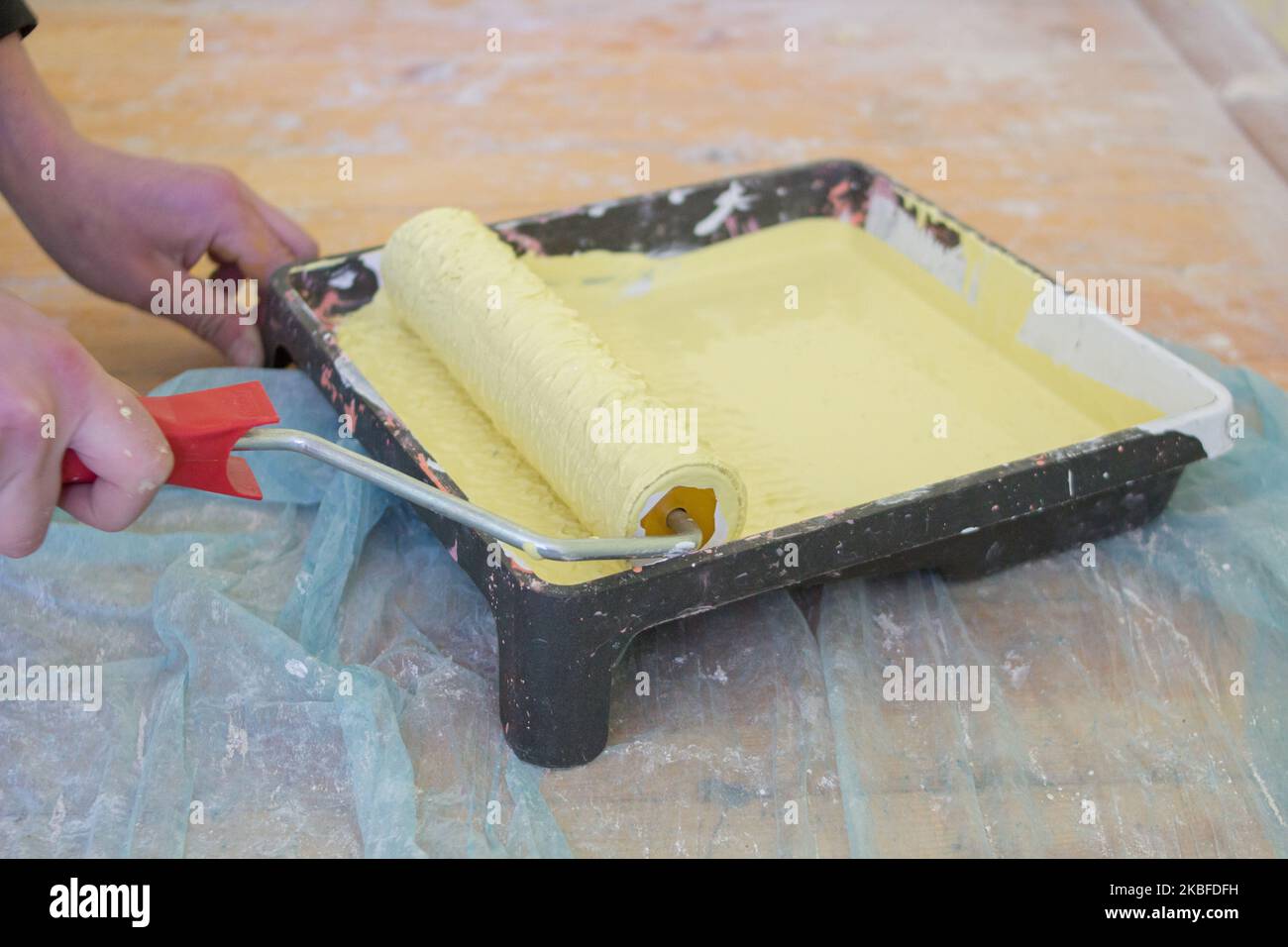 dipingere l'appartamento con un vassoio di vernice gialla e un utensile a rullo Foto Stock