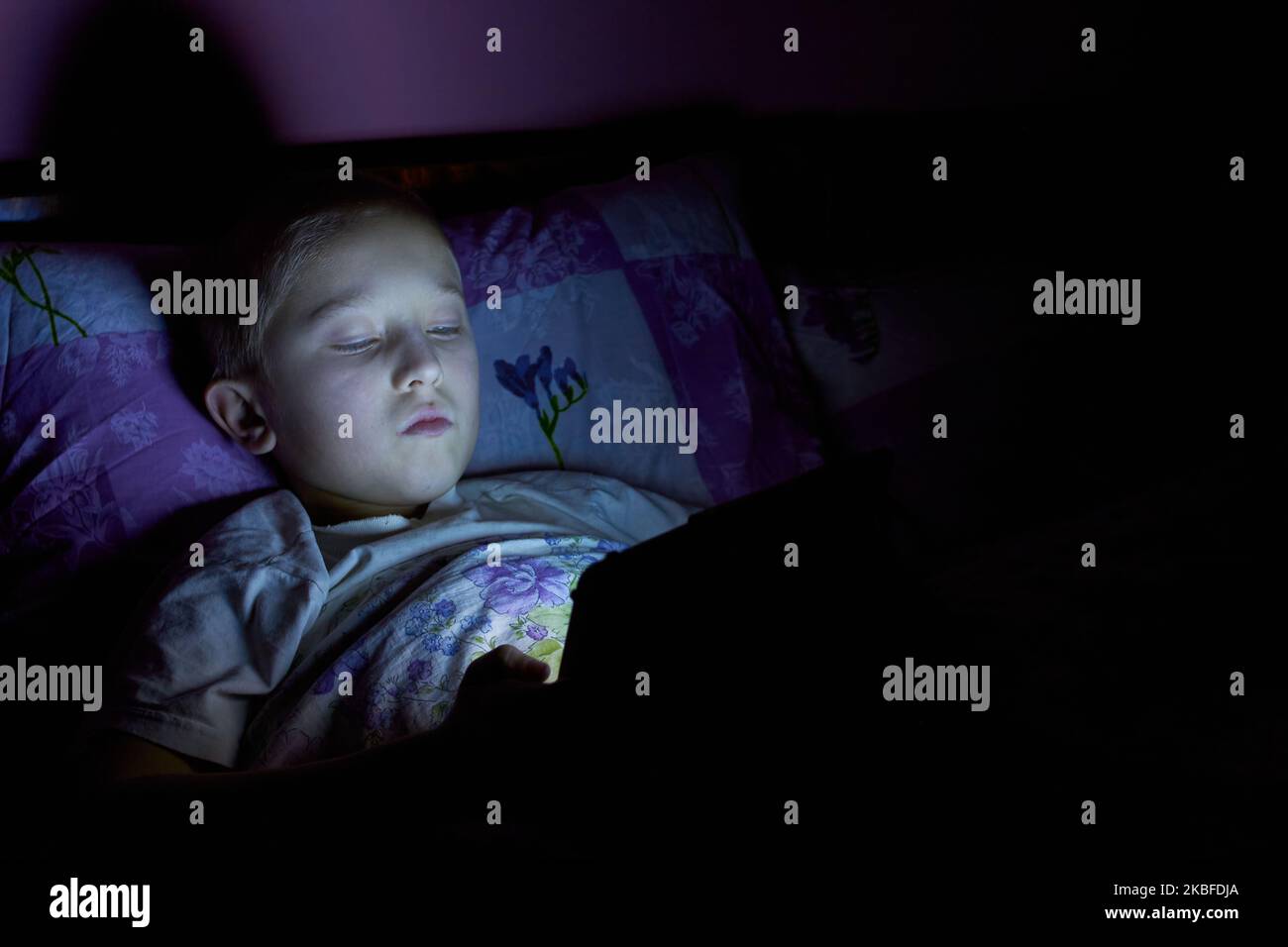 sul letto il ragazzo prima di andare a letto guarda la tavoletta Foto Stock