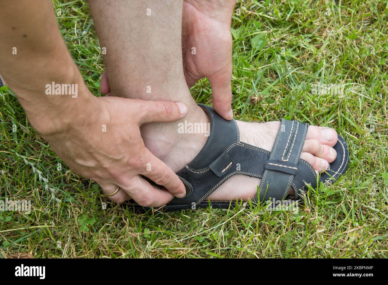 l'uomo si vestisce con i piedi di sandali sull'erba Foto Stock
