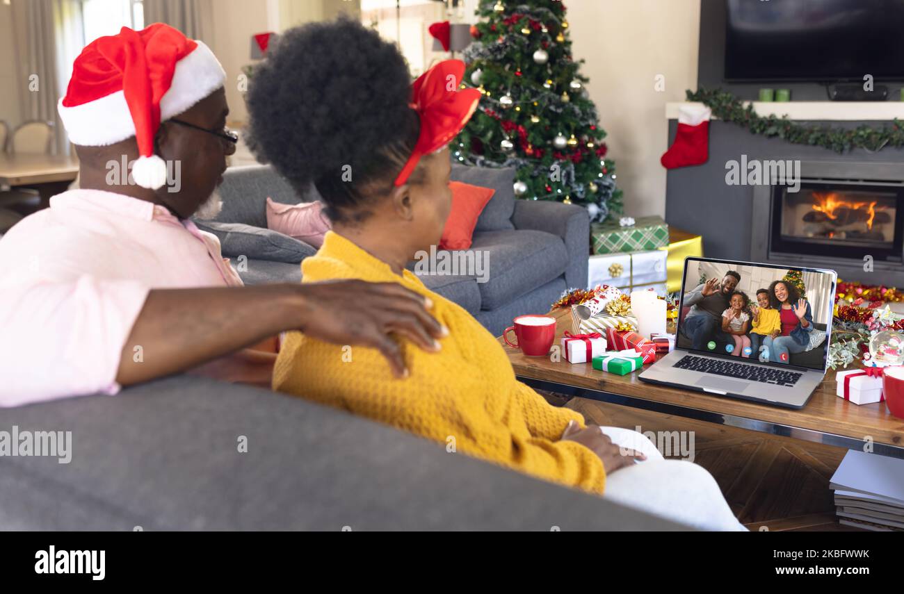 Coppia afro-americana con cappelli di babbo natale che ha videochiamata con felice famiglia afro-americana Foto Stock