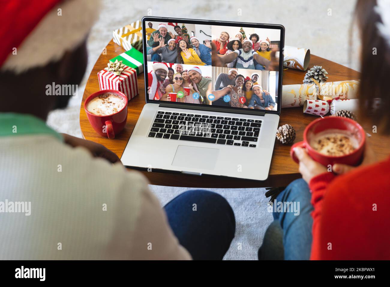 Coppia diversa con cappelli di babbo natale che hanno videochiamata con amici diversi felici Foto Stock