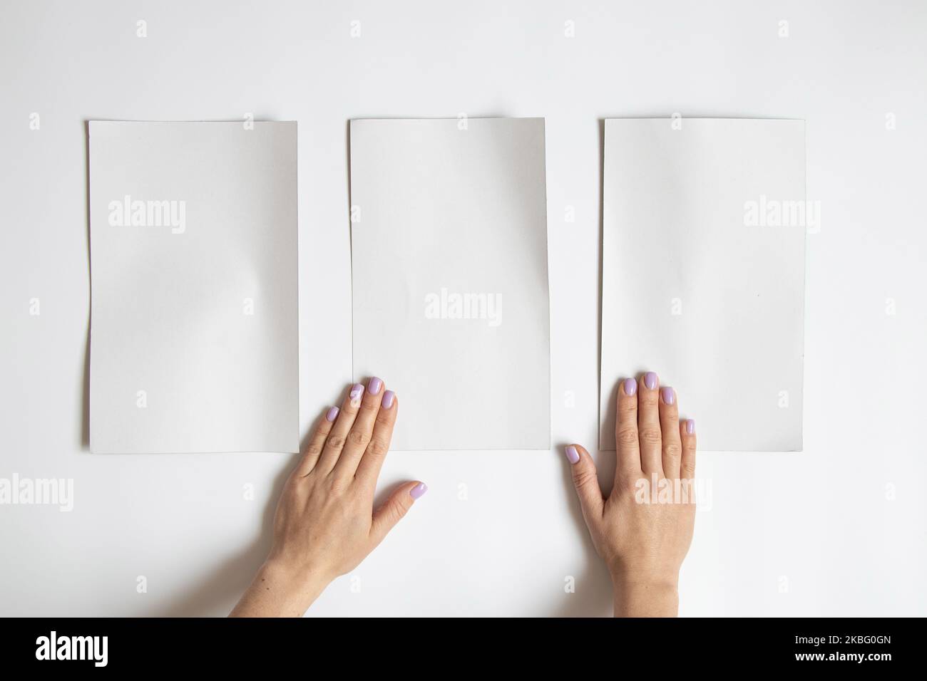 Cartoncini bianchi su sfondo bianco e mani femminili, spazio vuoto per il testo, blueprint Foto Stock