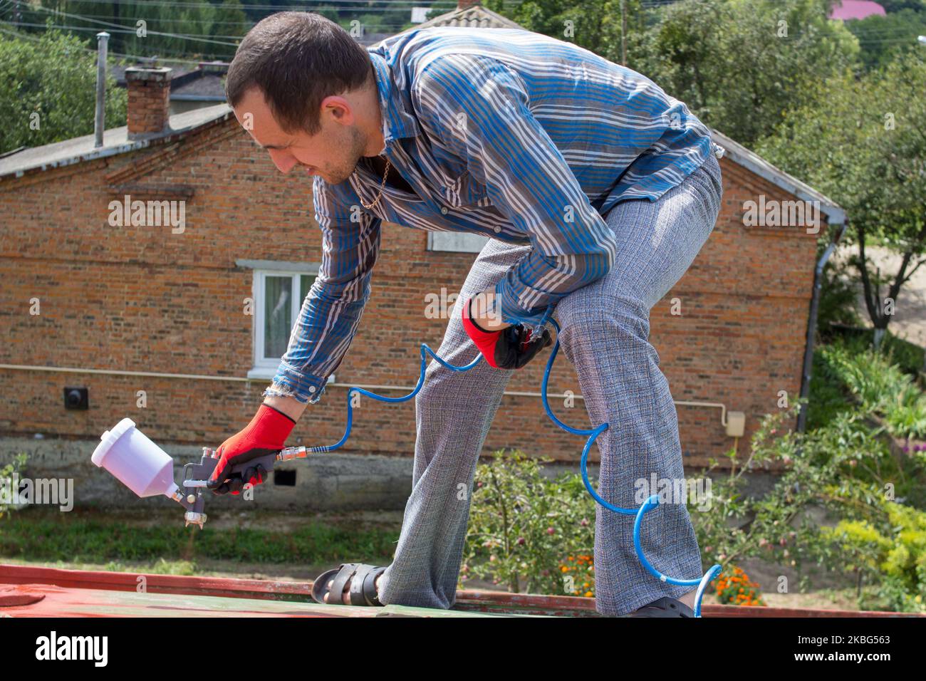 Un uomo dipinge un tetto senza un pizzo di assicurazione Foto Stock