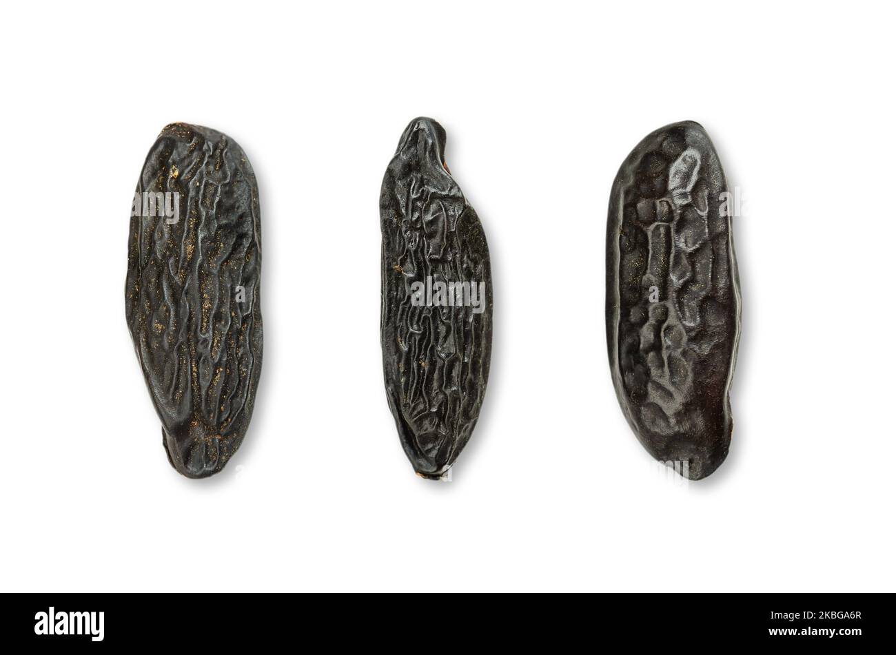 Three tonka beans, close-up, from above, on white background. Tonkin or tonquin beans, black and wrinkled seeds of the tree Dipteryx odorata. Foto Stock