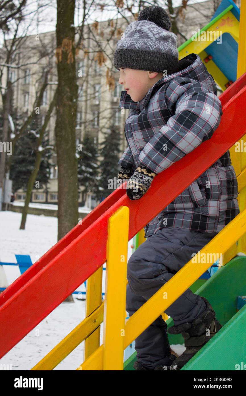 Carino bambino che si arrampica giù scala su piccola casa colorata al parco giochi Foto Stock