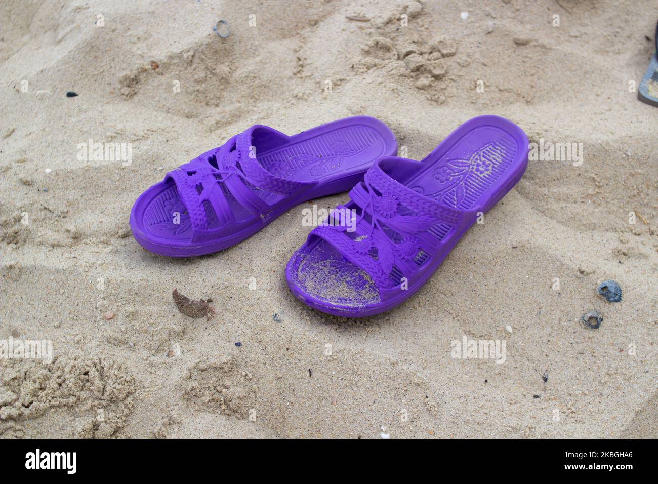 sulla sabbia sono le pantofole viola delle donne Foto Stock