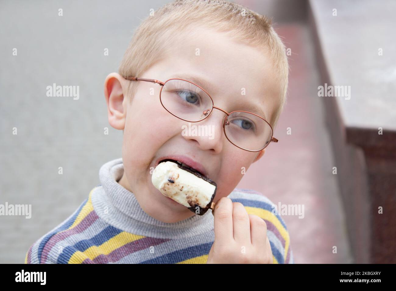 ritratto di un ragazzo con bicchieri che mangiano gelato al cioccolato su un bastone Foto Stock