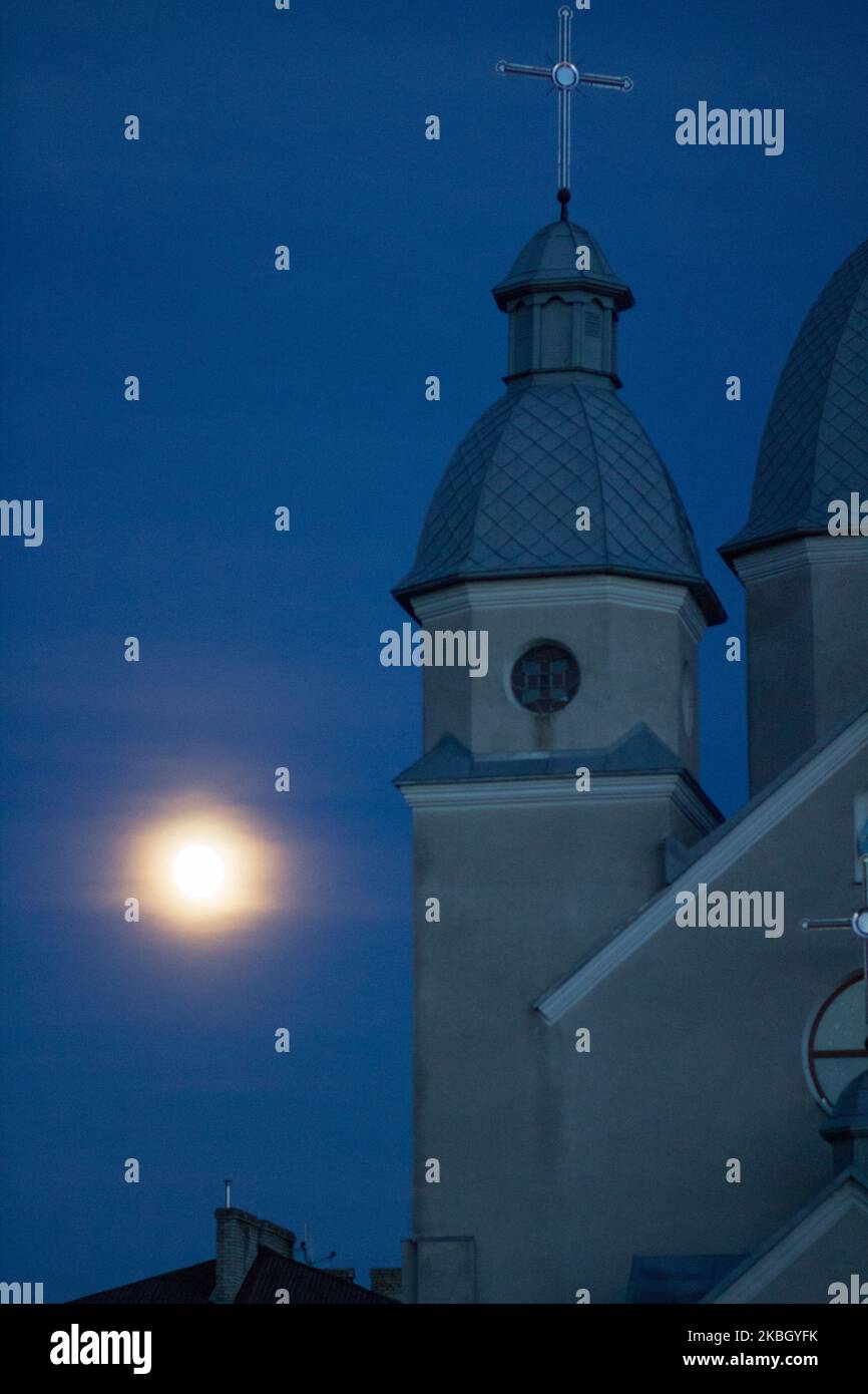 La chiesa cattolica di notte e una luna nel cielo brilla Foto Stock