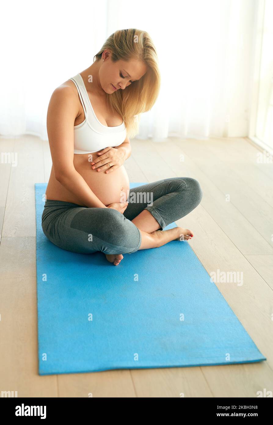 Fare mosse sane per il suo bambino ogni singolo giorno. Una donna incinta che lavora su un materassino per l'esercizio fisico a casa. Foto Stock