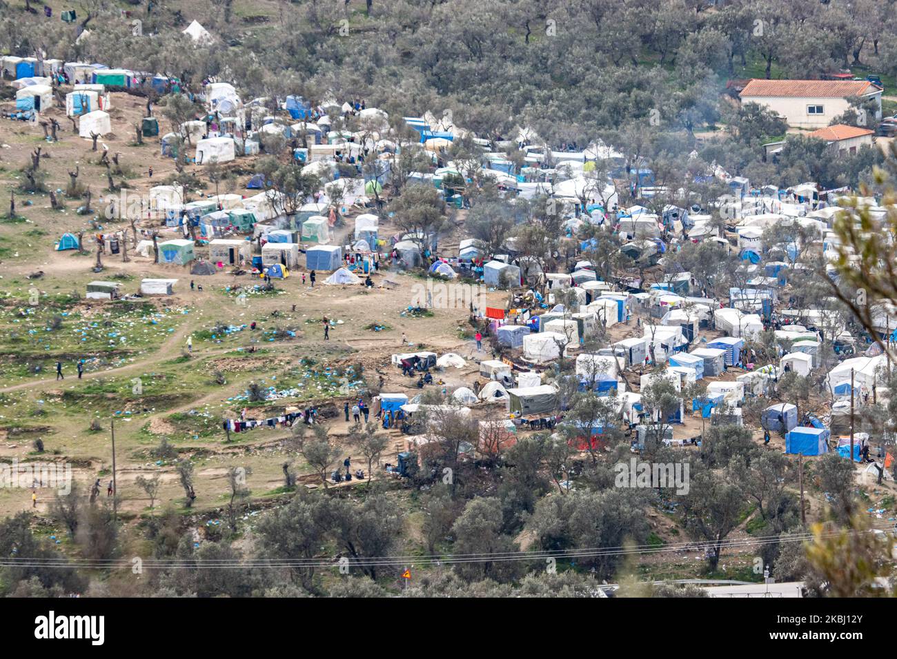 Panoramica generale e vista closeup da una collina della vita quotidiana a Moria. Tende fatte a mano sulle colline di uliveto delle baraccopoli o giungla o inferno come i richiedenti asilo lo hanno chiamato, accanto al primo centro ufficiale di accoglienza e identificazione, Moria hotspot. Moria campo di fortuna in cui le persone vivono nel fango senza strutture di base come l'accesso ad acqua, elettricità, calore, medici, ecc una minaccia per l'igiene, una bomba per la salute, dove i rifugiati hanno paura di malattie come il coronavirus. Il punto caldo ufficiale, campo e centro di registrazione nell'isola di Lesvos in Greece.There è una stima di 24,000 asylu Foto Stock