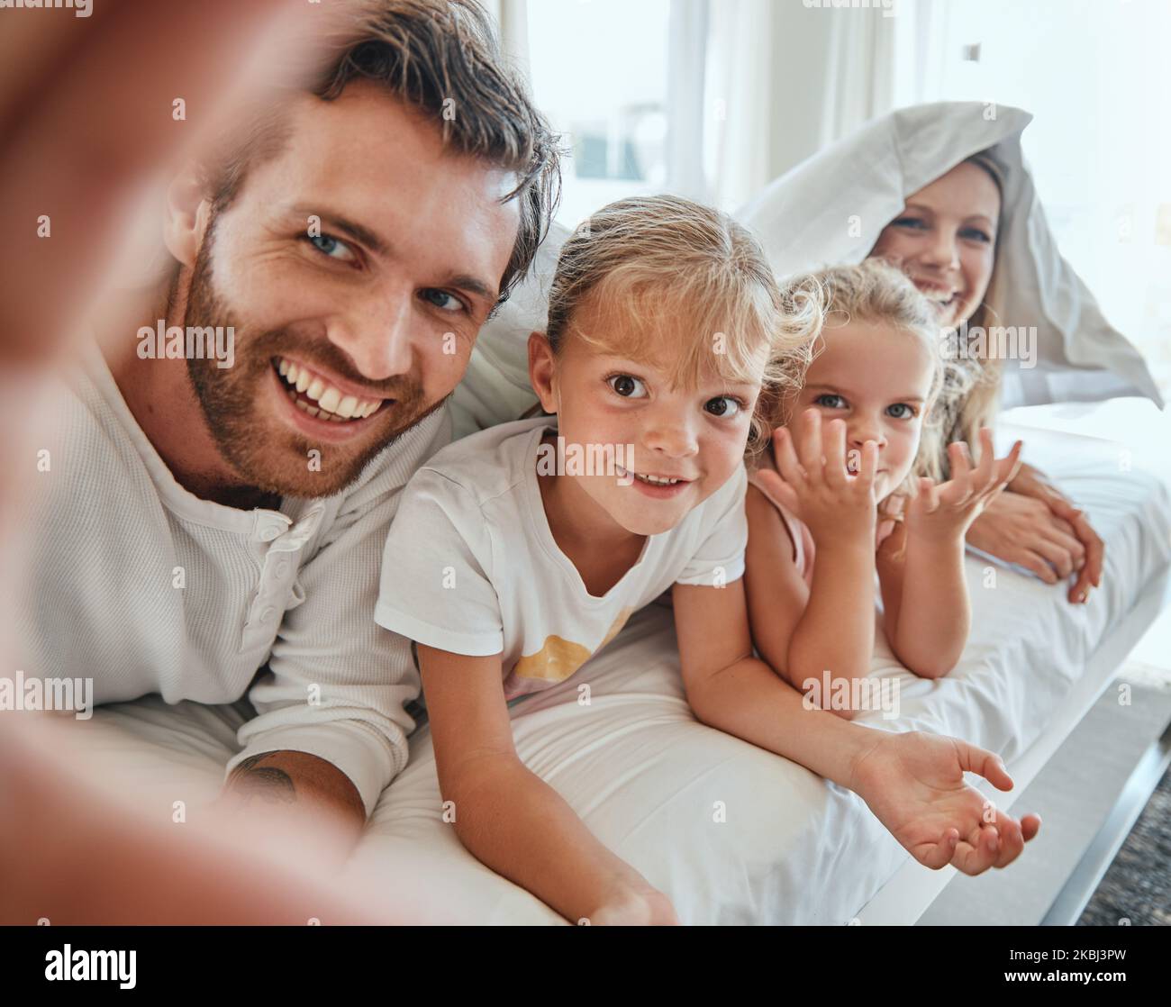 Selfie, famiglia e letto con genitori e bambini in posa per una fotografia insieme al mattino a casa. Camera da letto, amore e foto con una madre Foto Stock