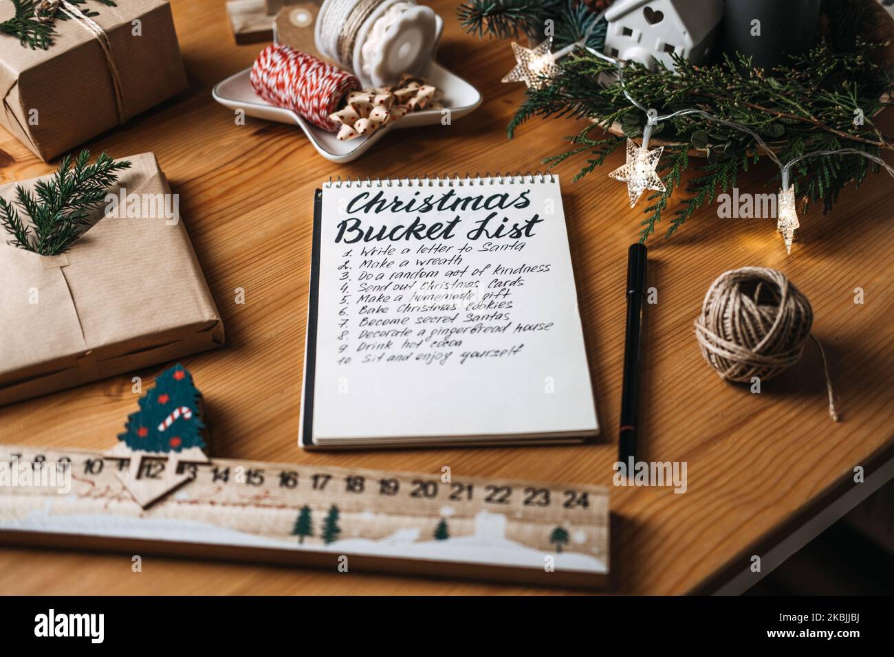Elenco del bucket di Natale, conto alla rovescia per la lista di controllo di Natale. Attività da svolgere in preparazione alle vacanze invernali. Donna scrive in un notebook per fare la lista per Foto Stock