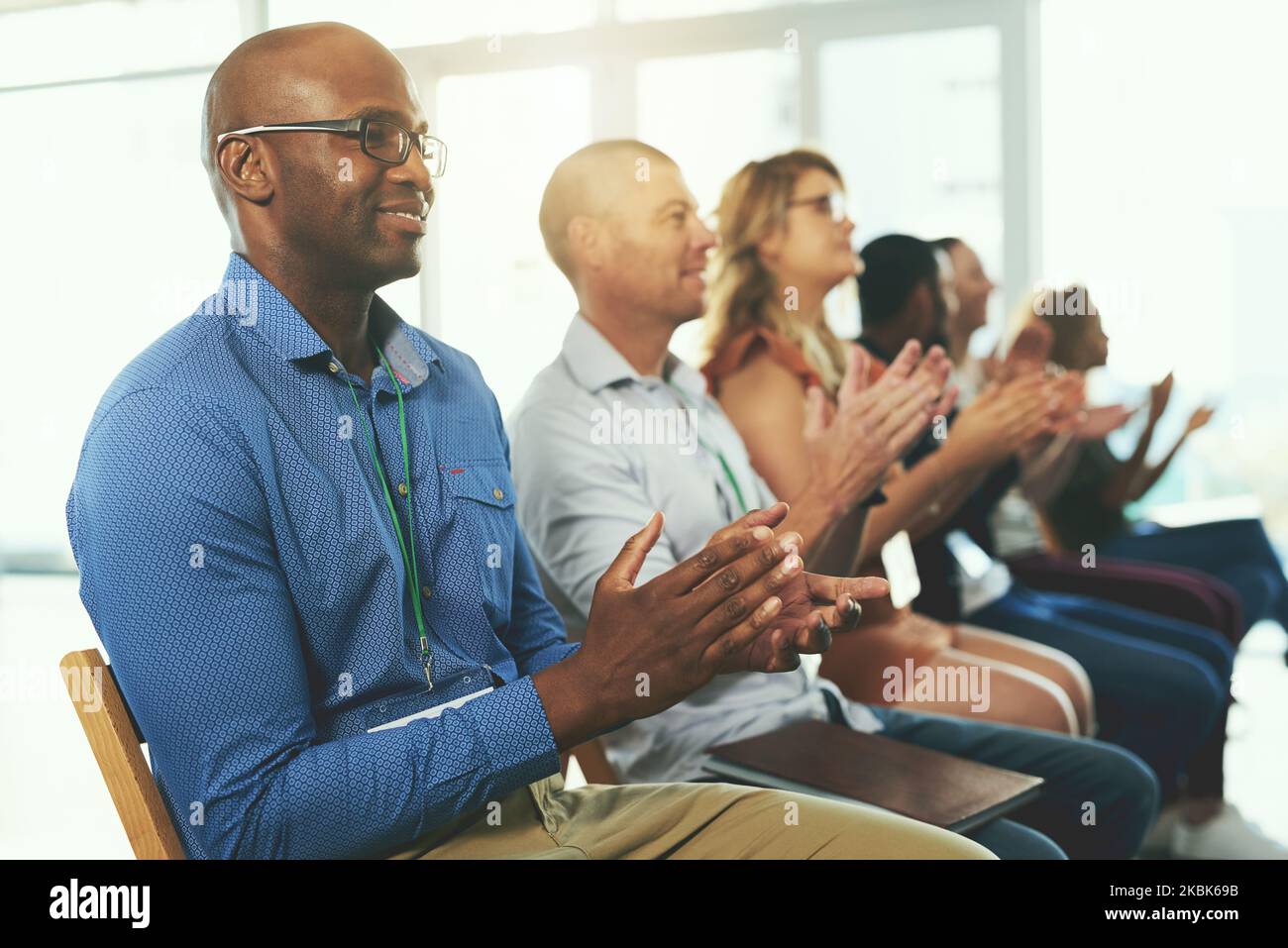 Fiero del loro progresso verso il successo. Un gruppo diversificato di dipendenti creativi applaudente all'interno. Foto Stock