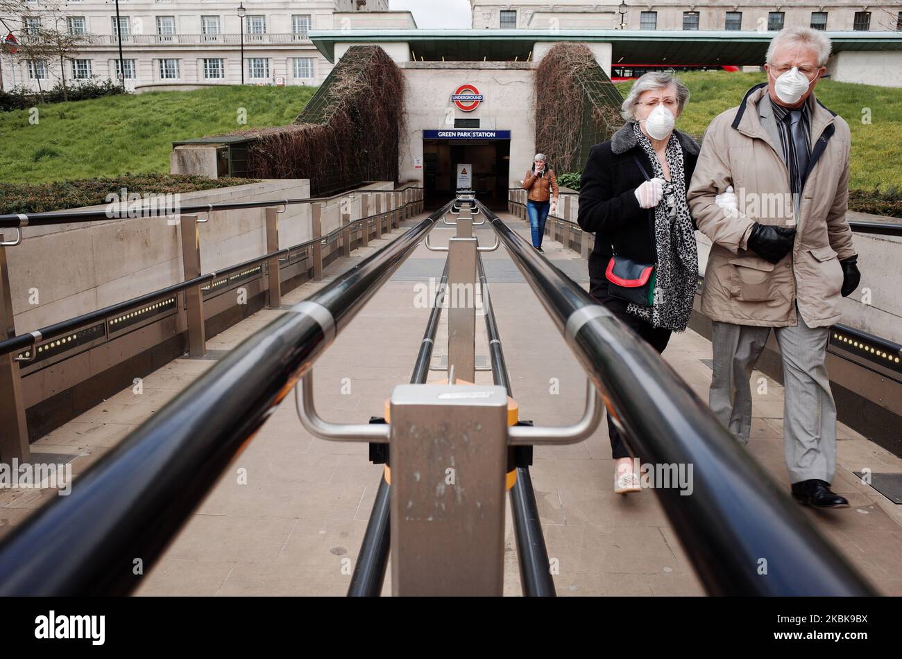 Una coppia anziana che indossa maschere facciali lascia la stazione della metropolitana Green Park a Londra, Inghilterra, il 20 marzo 2020. Nel Regno Unito è stato rivelato oggi che il gruppo consultivo scientifico per le emergenze (SAGE) del governo ha raccomandato di mantenere in vigore per la maggior parte dell'anno una qualche forma di "distensione sociale", con periodi alternati di restrizioni sempre più severe nel corso di quel periodo, per gestire la diffusione del coronavirus covid-19 e prevenire una schiacciante di ospedali. Le scuole stanno nel frattempo chiudendo oggi in tutto il paese fino a nuovo avviso, con eccezioni per i bambini vulnerabili Foto Stock