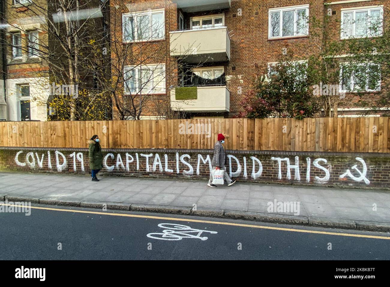 Le persone indossano maschere chirurgiche mentre camminano davanti a un graffito leggendo Covid19 capitalismo ha fatto questo a Londra Est il 21 marzo 2020 a Londra, Inghilterra. I londinesi sentono l'impatto degli arresti dovuti a Coronavirus. Il coronavirus (COVID-19) si è diffuso in almeno 186 paesi, mietendo più di 11.000 vittime e infettando più di 270.000 persone. Ci sono stati 3.983 casi diagnosticati nel Regno Unito e 177 morti, mentre l'Italia ha riportato altri 793 morti in un solo giorno nella peggiore crisi mondiale del coronavirus. (Foto di Alberto Pezzali/NurPhoto) Foto Stock