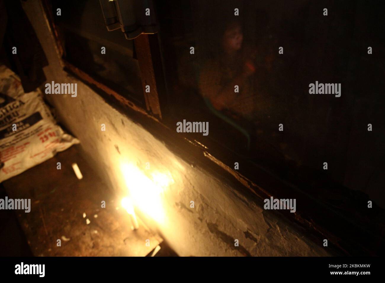 Una donna con smartphone siede sulla terrazza della sua casa illuminata da luci di candela mentre partecipa all'evento Earth Hour 2020 spegnendo le luci elettriche di herr nel villaggio di Wanasari, provincia di Giava Occidentale, Indonesia, il 28 marzo 2020. Earth Hour è un movimento mondiale annuale organizzato dal World Wide Fund for Nature (WWF), che incoraggia gli individui, le comunità e le imprese a spegnere le luci elettriche non essenziali per un'ora, dalle 8:30 alle 9:30 in un giorno specifico alla fine di marzo, come simbolo di impegno per il pianeta. (Foto di Aditya Irawan/NurPhoto) Foto Stock