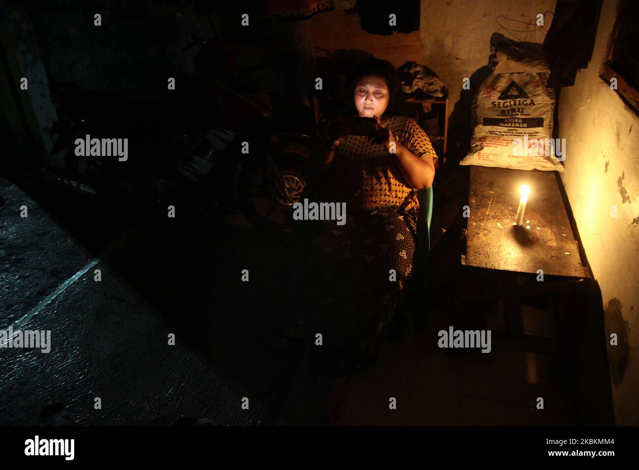 Una donna con smartphone siede sulla terrazza della sua casa illuminata da luci di candela mentre partecipa all'evento Earth Hour 2020 spegnendo le luci elettriche di herr nel villaggio di Wanasari, provincia di Giava Occidentale, Indonesia, il 28 marzo 2020. Earth Hour è un movimento mondiale annuale organizzato dal World Wide Fund for Nature (WWF), che incoraggia gli individui, le comunità e le imprese a spegnere le luci elettriche non essenziali per un'ora, dalle 8:30 alle 9:30 in un giorno specifico alla fine di marzo, come simbolo di impegno per il pianeta. (Foto di Aditya Irawan/NurPhoto) Foto Stock