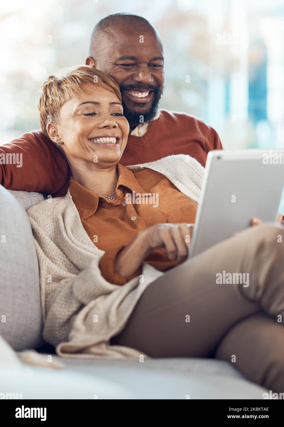 Coppia nera, rilassati e sorridi con un tablet per l'intrattenimento online insieme sul divano del soggiorno di casa. Felice uomo e donna che si rilassano nella felicità Foto Stock