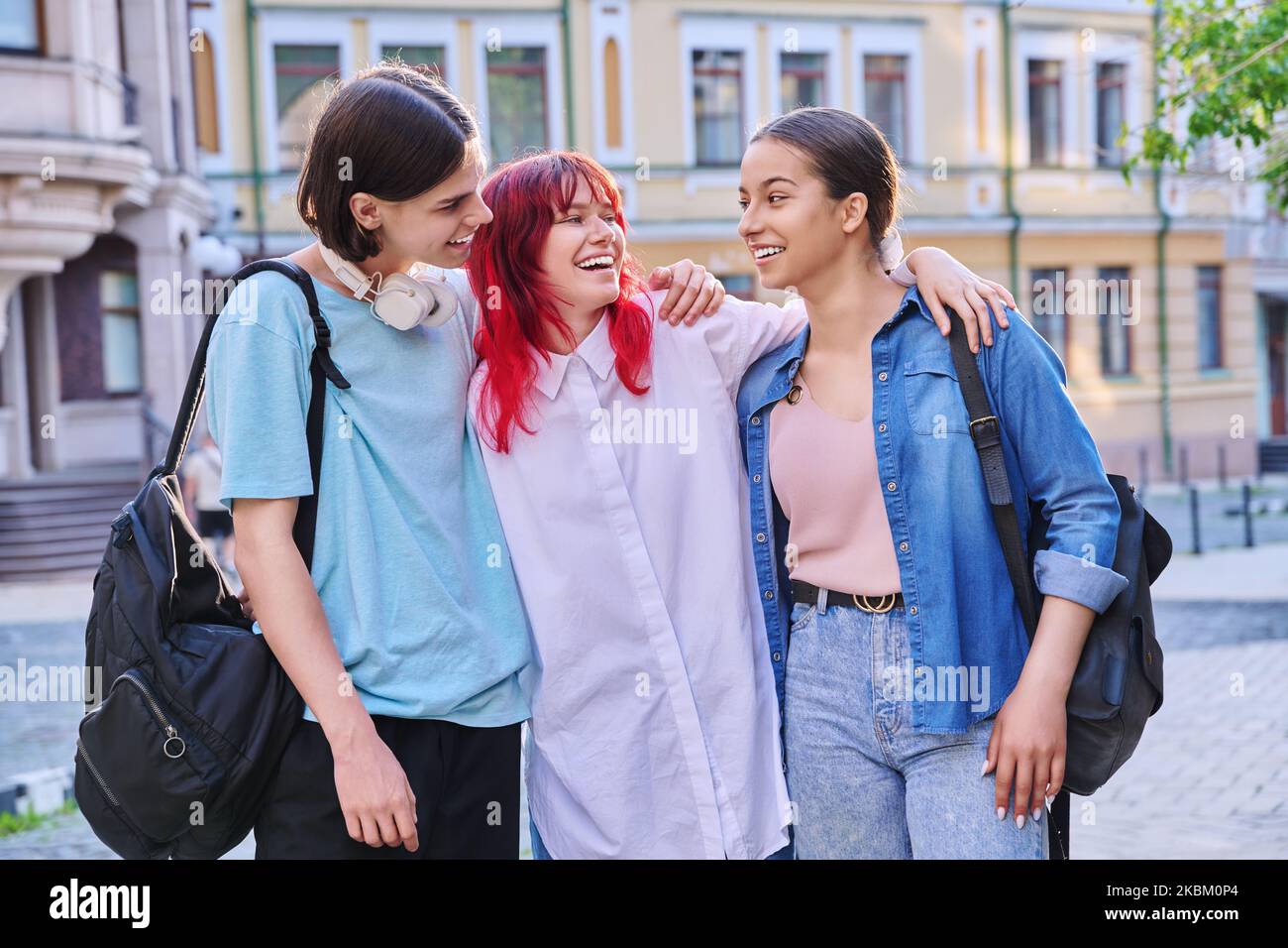 Felice sorridendo abbracciando gli amici adolescenti all'aperto, sulla strada della città Foto Stock