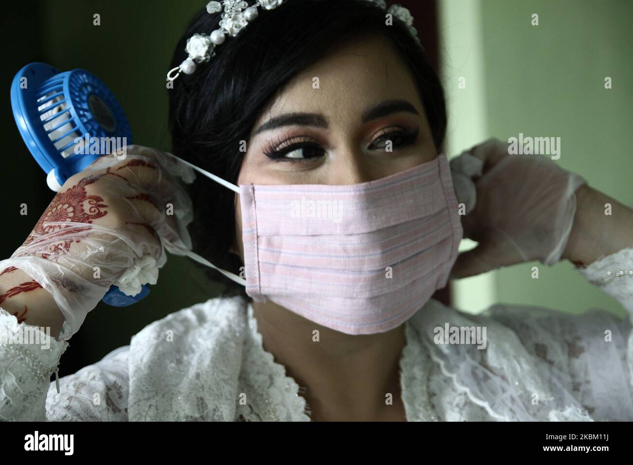 La coppia ha carezzato fuori il loro matrimonio usando la maschera protettiva del viso e guanti di lattice in preoccupazione di coronavirus (Covid-19) a Giacarta, il 5 aprile 2020. Il governo indonesiano ha limitato la politica di allontanamento fisico in seguito al numero di casi di coronavirus in aumento, che a partire da aprile 4 avevano superato i 2,092 casi in tutto il paese, con 191 morti e 150 guariti. (Foto di Aditya Irawan/NurPhoto) Foto Stock
