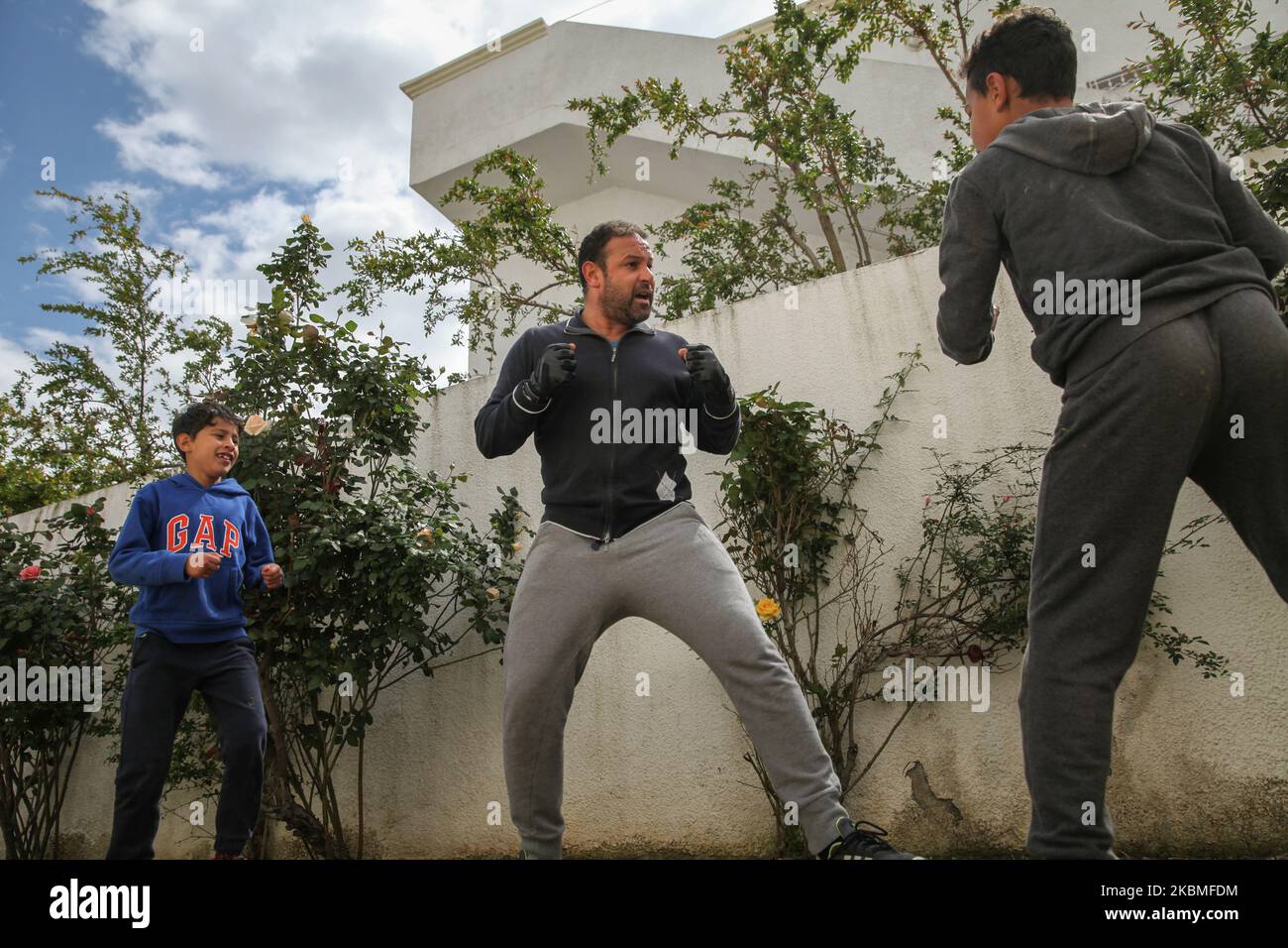 Un padre che combatte contro i suoi due figli adolescenti, mentre praticano Karate nel cortile di casa, nel governatorato di Ariana, nel nord della Tunisia, mentre cercano di scacciare la vacuità, Lo stress e di rimanere in forma durante il blocco generale imposto dalle autorità tunisine nel tentativo di rallentare la diffusione del nuovo focolaio di coronavirus che causa la malattia di Covid-19 in Tunisia, il 26 marzo 2020. (Foto di Chardy ben Ibrahim/NurPhoto) Foto Stock