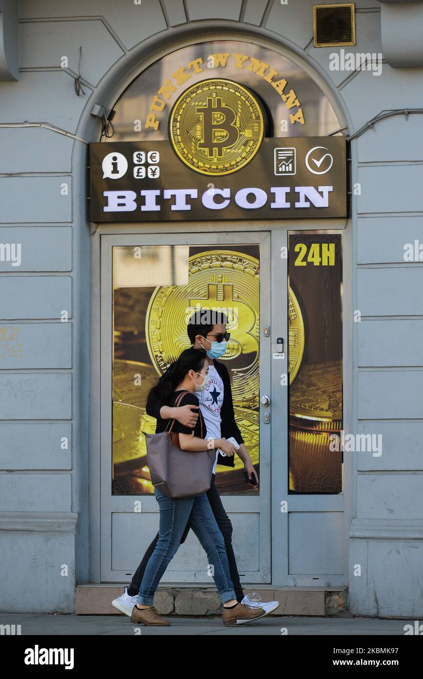 Una coppia che indossa maschere mediche passa davanti a un negozio di scambio Bitcoin nel centro di Cracovia. Sabato 18 aprile 2020 a Cracovia, Polonia. (Foto di Artur Widak/NurPhoto) Foto Stock