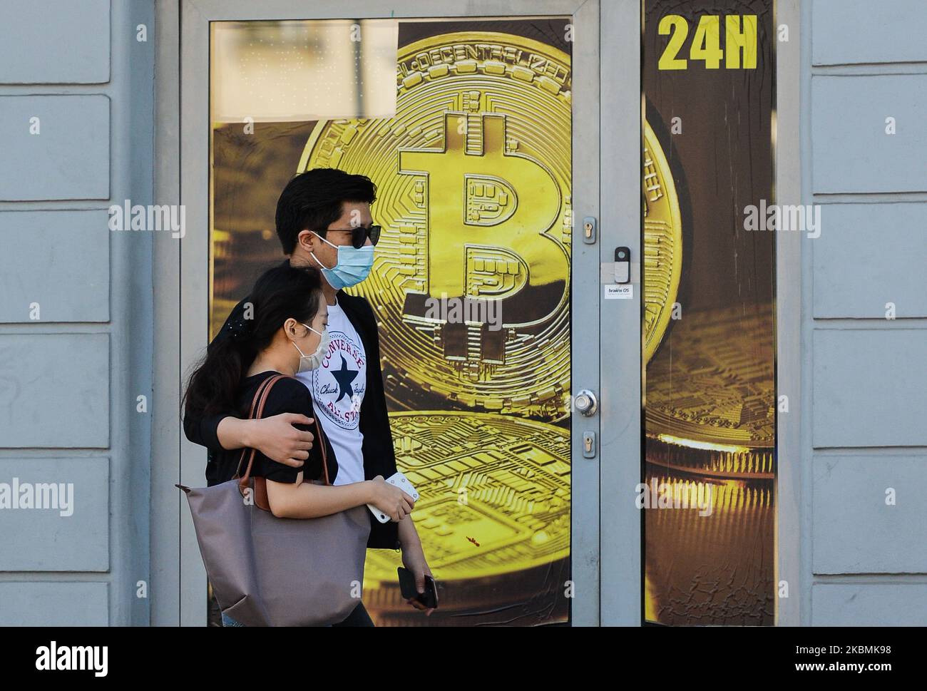 Una coppia che indossa maschere mediche passa davanti a un negozio di scambio Bitcoin nel centro di Cracovia. Sabato 18 aprile 2020 a Cracovia, Polonia. (Foto di Artur Widak/NurPhoto) Foto Stock