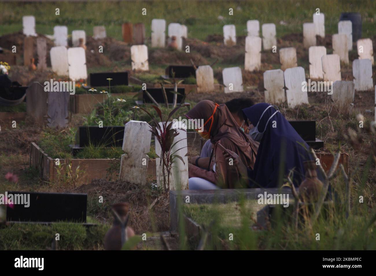 I pellegrini visitano la tomba della loro famiglia per pregare e seminare fiori che hanno acquistato dal venditore di fiori della tomba, la signora Gumih (45) in anticipo il mese santo di Ramadhan al cimitero pubblico nel villaggio di Wanajaya, la reggenza di Bekasi, provincia di Giava Occidentale, il 22 aprile 2020. La signora Gumih (45) e suo marito Amin (48), servono i pellegrini dal 2005 vendendo fiori di tomba di fronte al cimitero, che alcuni dei tipi di fiori sono raccolti dai giardini di fiori piantati intorno alla loro casa. (Foto di Aditya Irawan/NurPhoto) Foto Stock