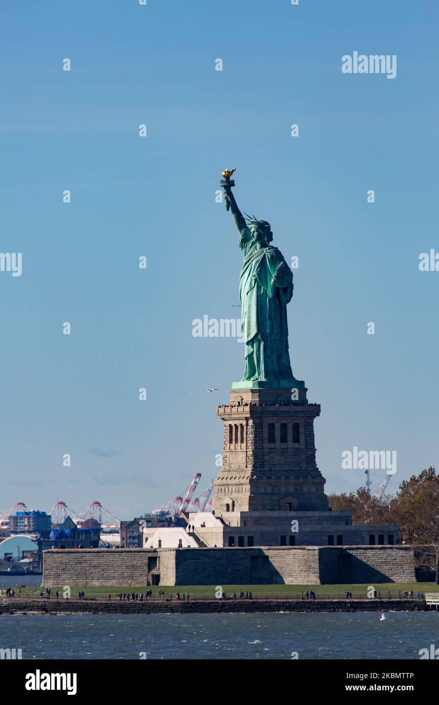 Statua della libertà come si vede durante una giornata senza nuvole con il cielo blu con turisti e visitatori a Liberty Island Manhattan, New York City, Stati Uniti, da un traghetto in mare. L'iconica statua in rame raggiunge i 93m metri sopra il mare ed è stata dedicata il 28 ottobre 1886. Fu progettata dallo scultore francese Frédéric Auguste Bartholdi e la sua struttura metallica fu costruita da Gustave Eiffel, la scultura fu un dono del popolo francese. Oggi è una popolare attrazione turistica, una destinazione di viaggio, punto di riferimento per NYC e gli Stati Uniti, uno dei simboli più riconoscibili al mondo. La statua è una figura di Foto Stock