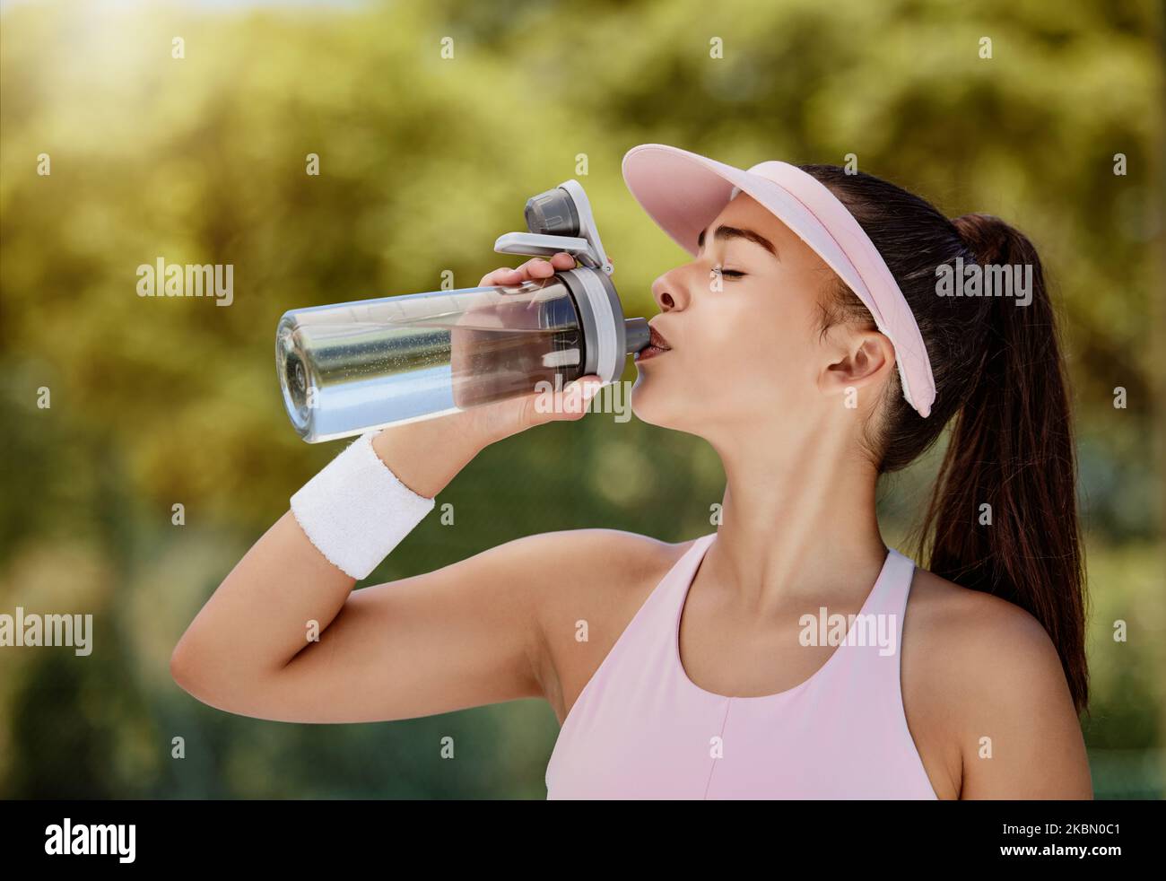 Donna bottiglia d'acqua potabile in pausa al gioco di tennis, allenamento o allenamento in estate per l'idratazione. Tennista ragazza, bere liquido per la salute Foto Stock