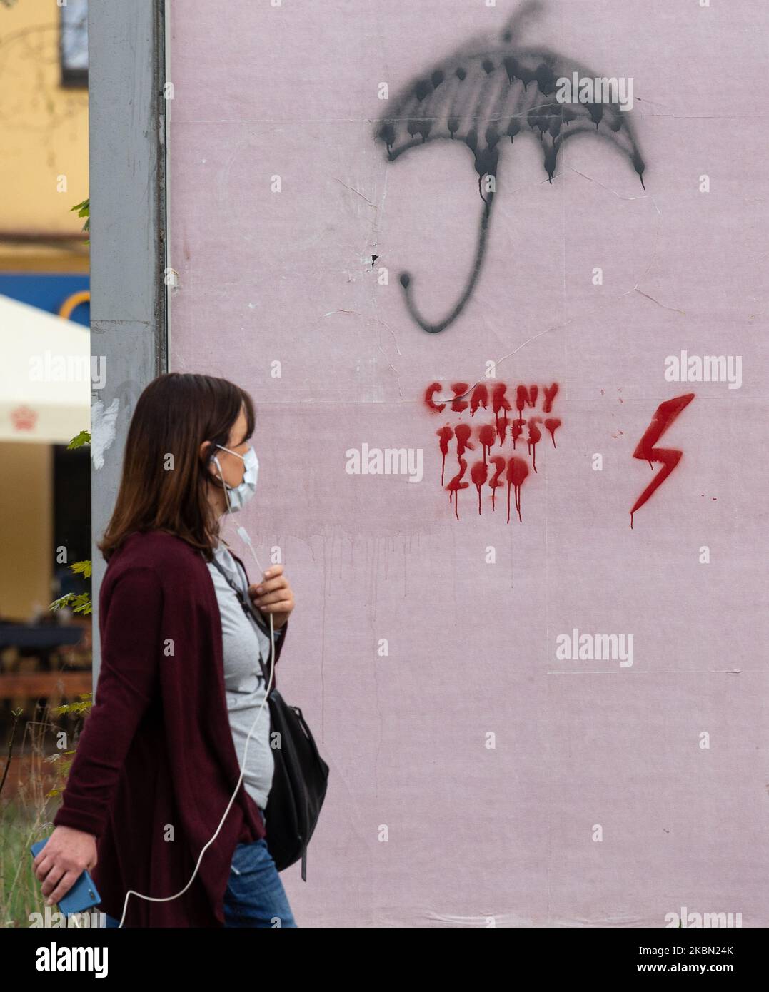 Una donna in maschera protettiva è visto passando un graffito di protesta nera con luce rossa - un segno di sciopero delle donne in Polonia in un centro di Cracovia durante la pandemia di Covid-19 il 28 aprile 2020. Le donne hanno lanciato una protesta, chiamata anche Inferno polacco, contro una politica di aborto attualmente discussa in parlamento polacco che abolisce l'aborto anche in caso di problemi di salute. (Foto di Dominika Zarzycka/NurPhoto) Foto Stock